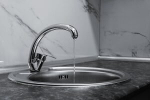 Σύγχρονη βρύση κουζίνας με τρεχούμενο νερό σε νεροχύτη ανοξείδωτο